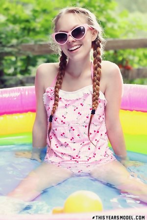 Petite blonde teen Dolly Little with tiny tits poses naked outdoors in the pool