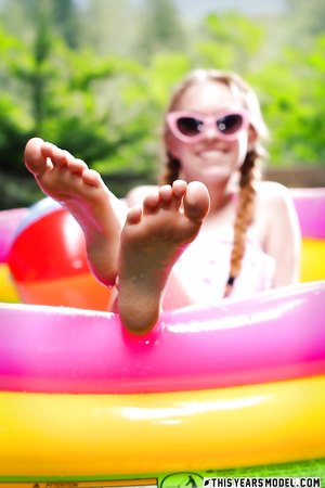 Petite blonde teen Dolly Little with tiny tits poses naked outdoors in the pool