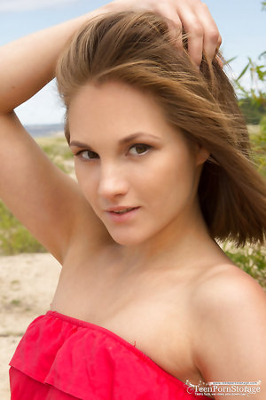 Slender blonde Selena fingering her shaved pussy on the sand