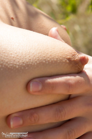 Slender blonde Selena fingering her shaved pussy on the sand