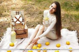Thin Leona Mia undresses outside in green grass with lemons to show long legs